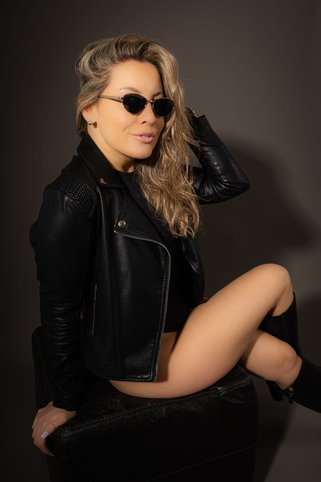 A personal-branding portrait in a leather jacket against charcoal