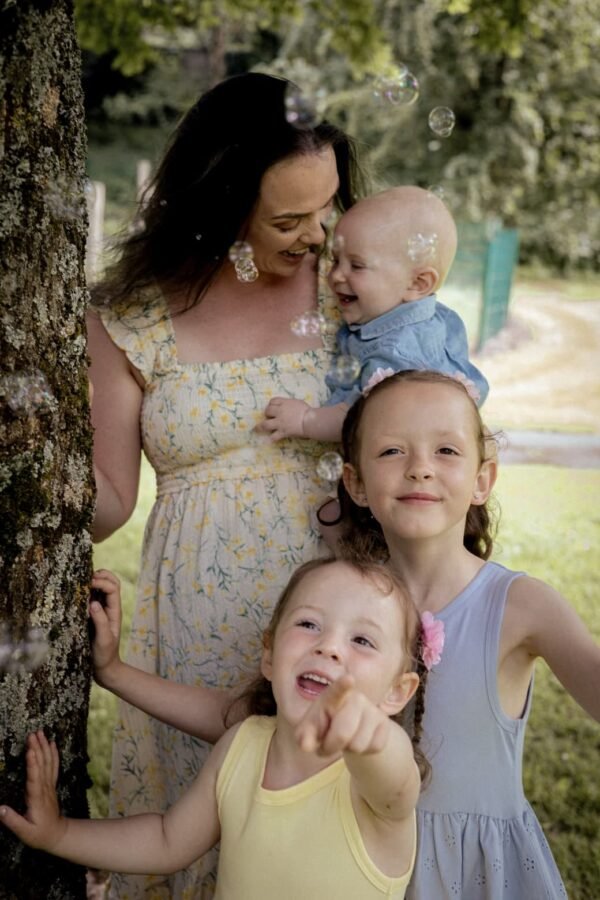 A mother with her three children blowing bubbles in the garden
