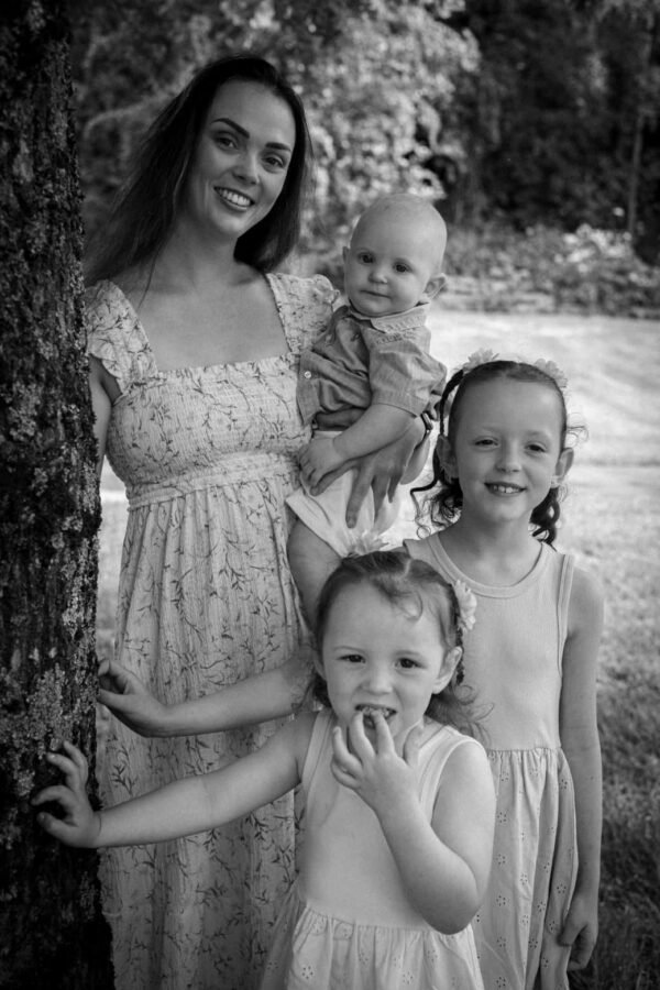 A mother with her three children by a tree, in black and white