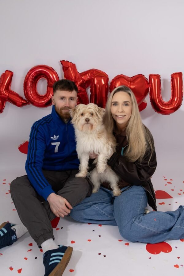 A couple with their dog among heart balloons
