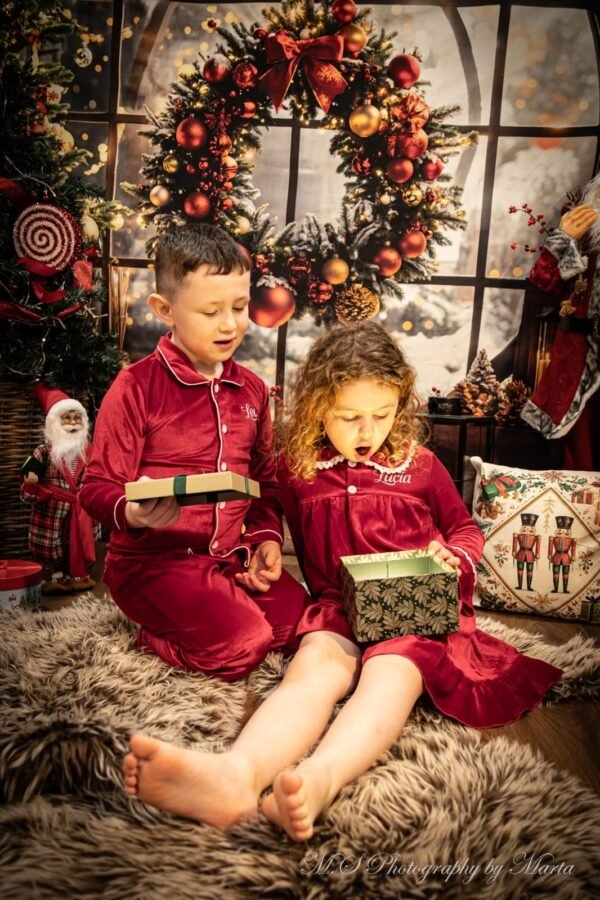 Two children in red at a festive Christmas set