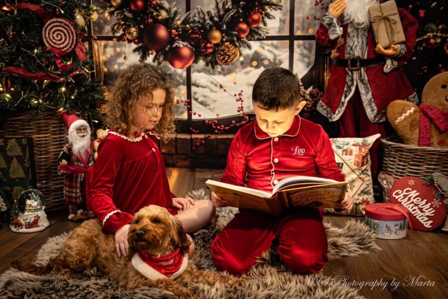 Children reading with their dog at a Christmas set